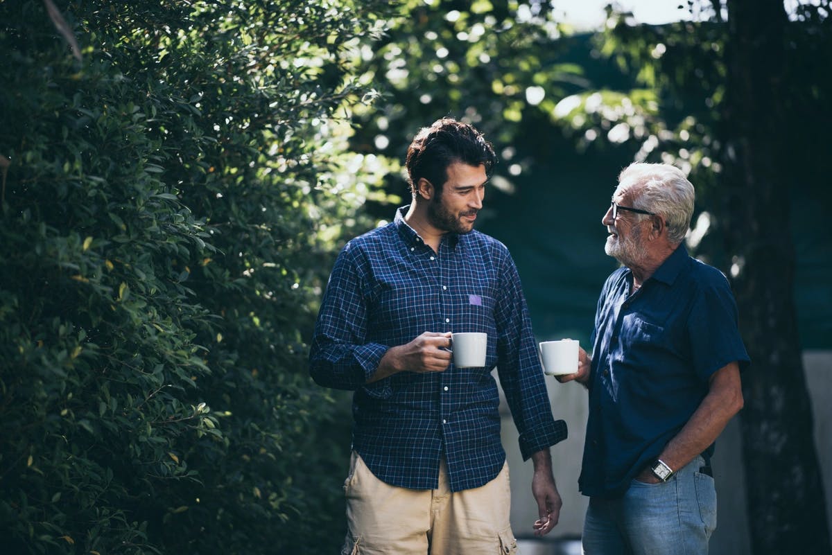 two men outside with coffee mugs